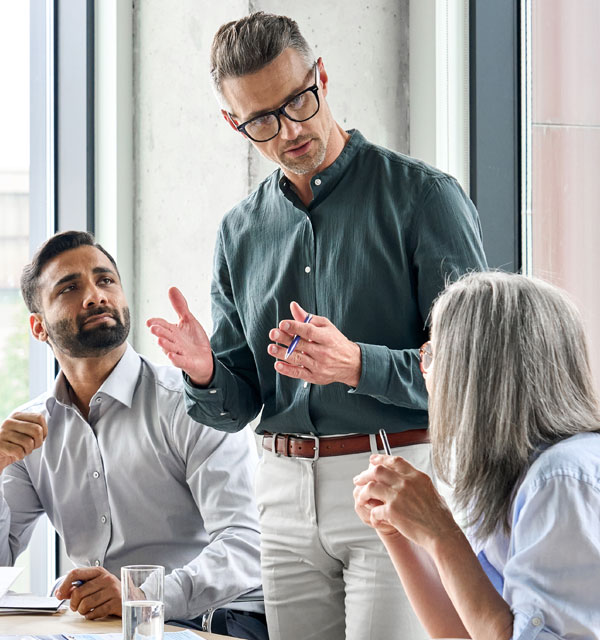 Mature businessman leader mentor talking to diverse colleagues team listening to the ceo. 