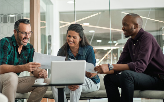 Casual meeting of smiling diverse business team analyzing financial data.