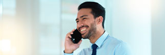 Business man talking on a phone while browsing on a digital tablet in an office.